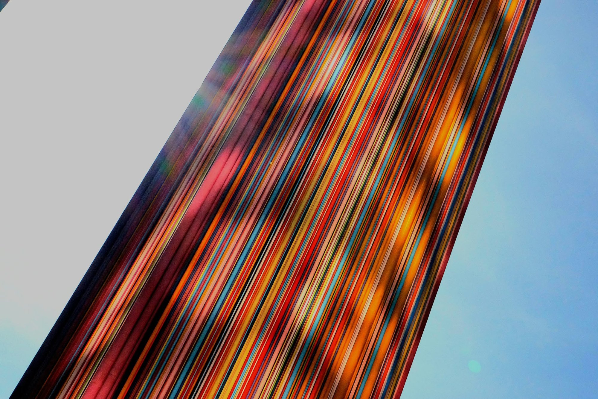 The coloured tubes crossing the frame on a diagonal against a pale sky
