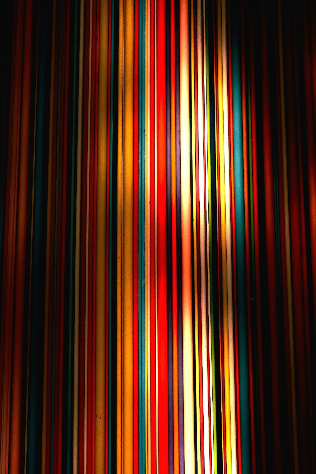 The tubes lit like a curtain of coloured stripes fading into black