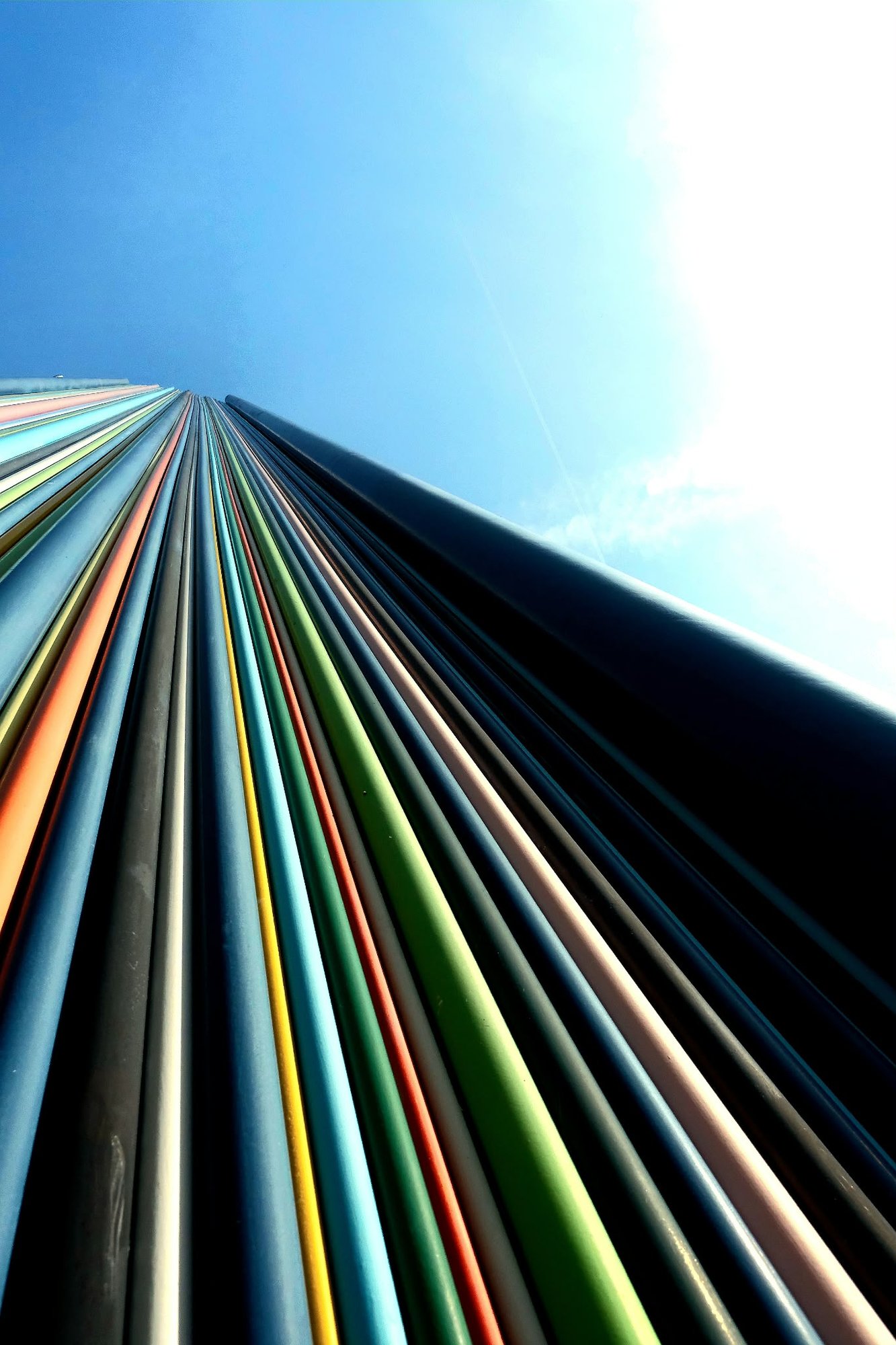 Looking straight up the coloured tubes as they converge in a blue sky