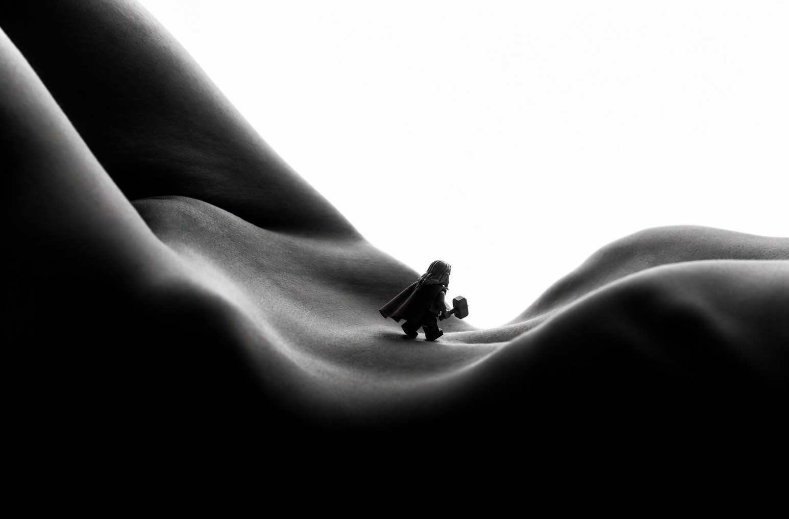 Minithor, a tiny caped figure, crossing a valley of skin