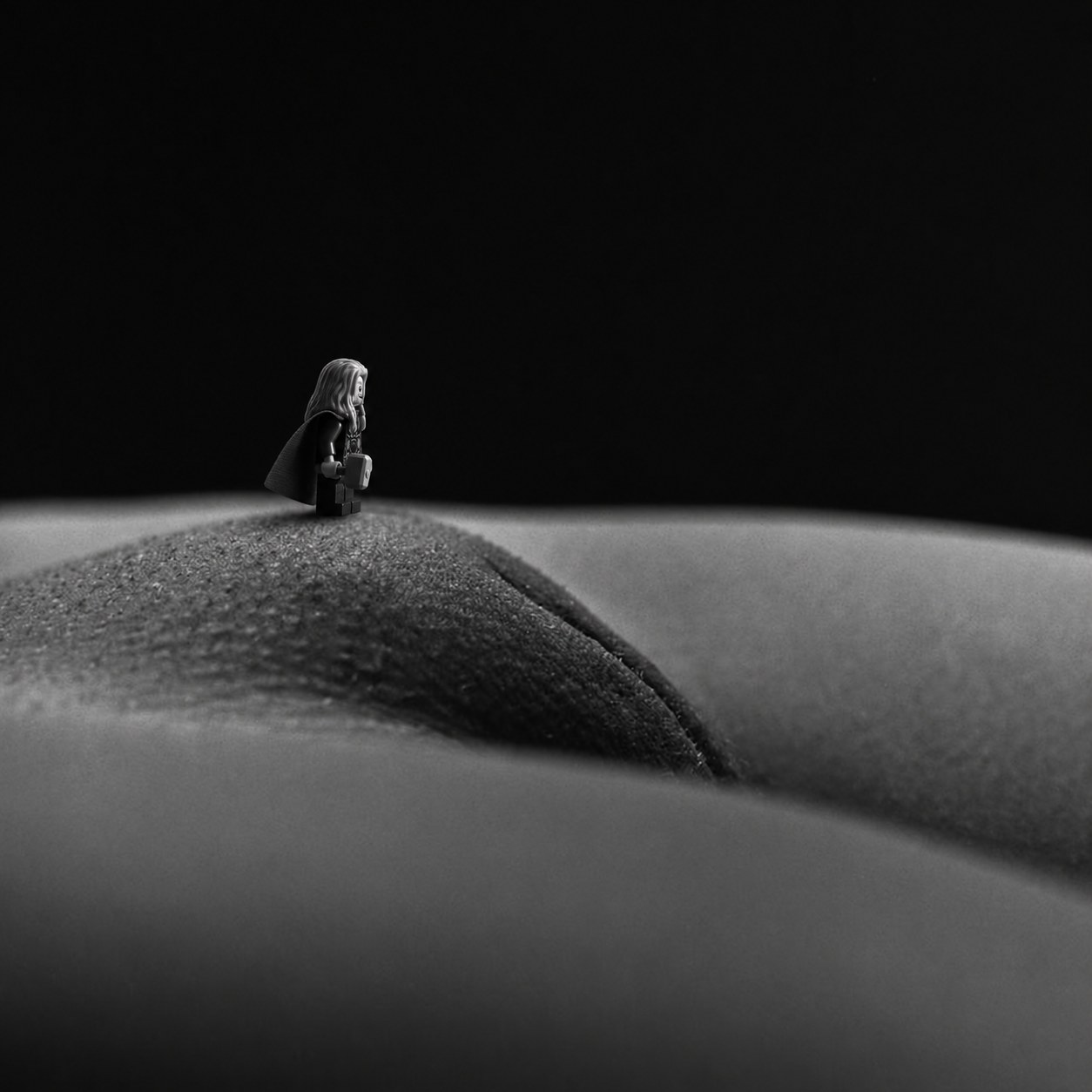 The figure stands on a ridge of skin against darkness
